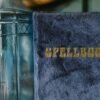 A velvet-bound spellbook beside an ornamental glass bottle, evoking mystery and magic.