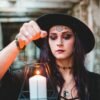A woman in gothic attire holding a candle lantern, evoking a mystical atmosphere.